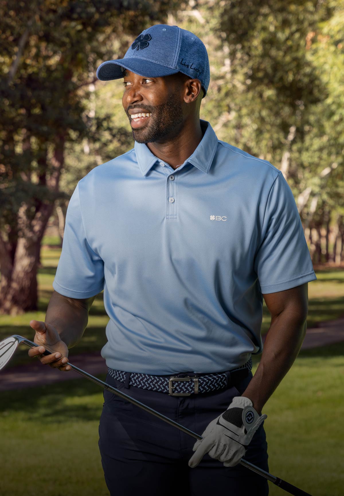 Man wearing Black Clover apparel at golf course holding golf club