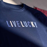 A blue, red, and green t-shirt featuring the text "Live Lucky" on a grey background.