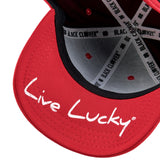 Bold, red hat from Black Clover featuring premium style and craftmanship. It features an embroidered black clover icon, and the words "Live Lucky" on the side.