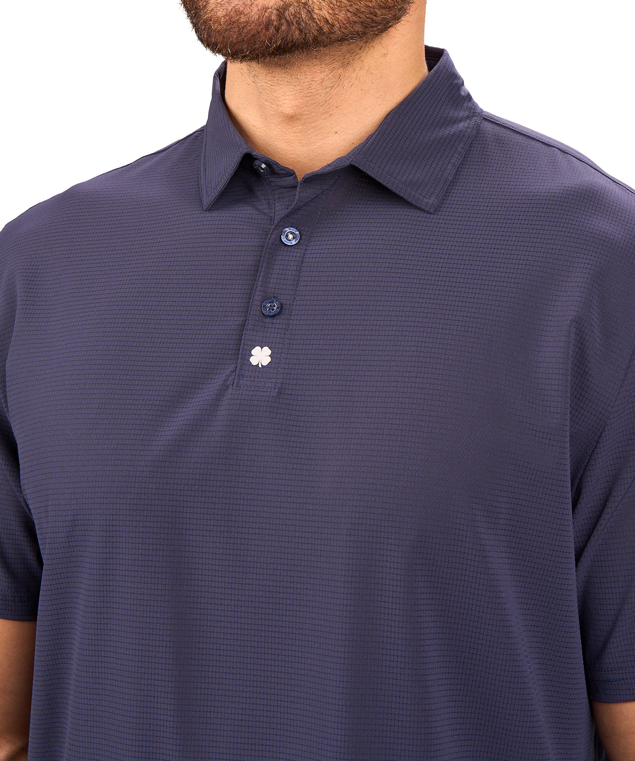 Man wearing navy polo from Black Clover with a small clover near the buttons