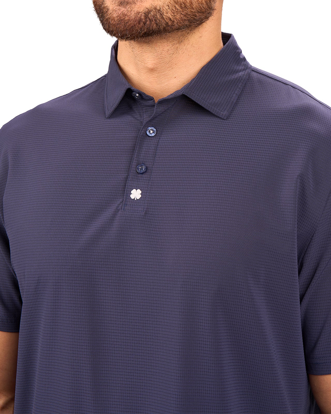 Man wearing navy polo from Black Clover with a small clover near the buttons