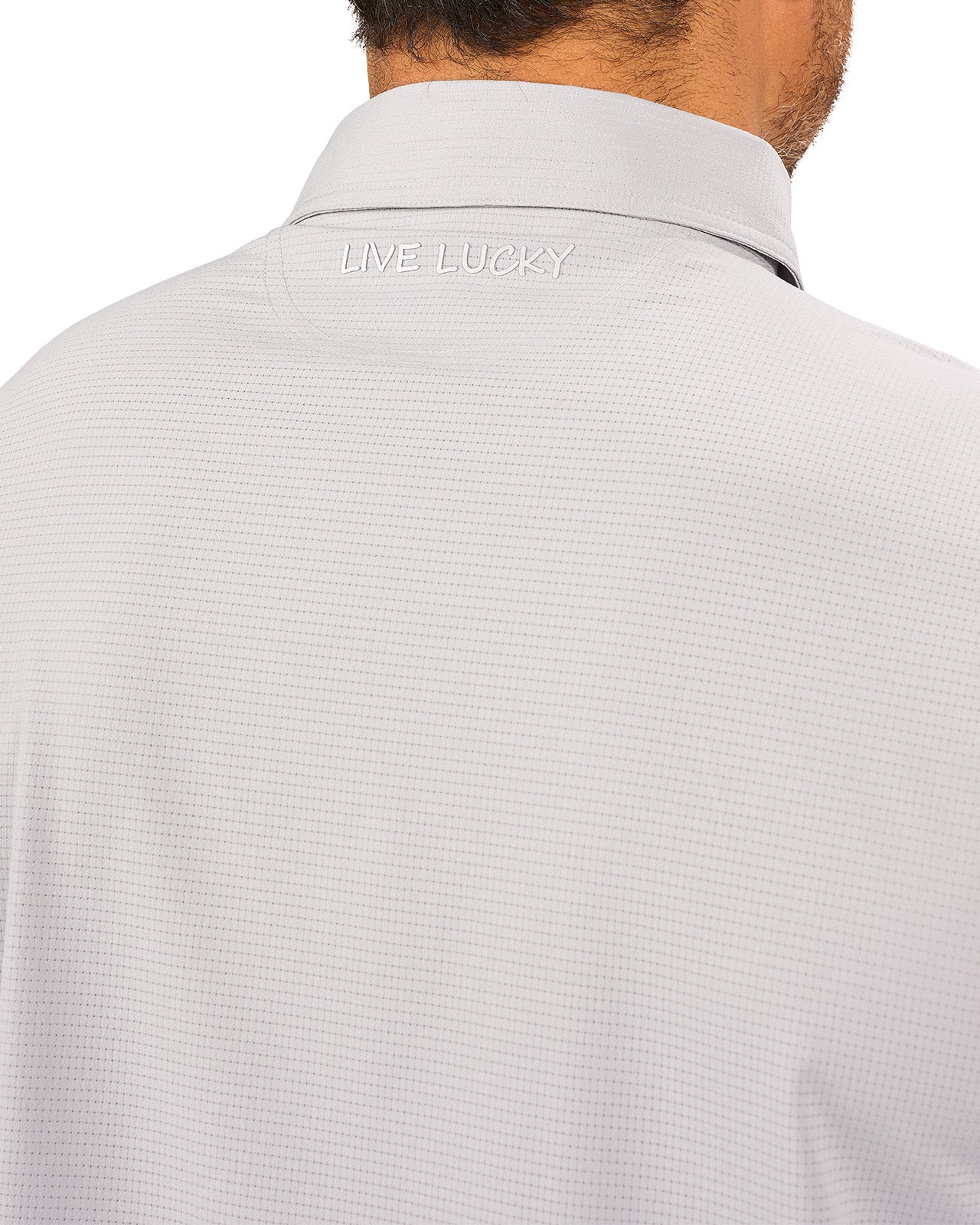 Man wearing light grey polo from Black Clover with a small clover near the buttons