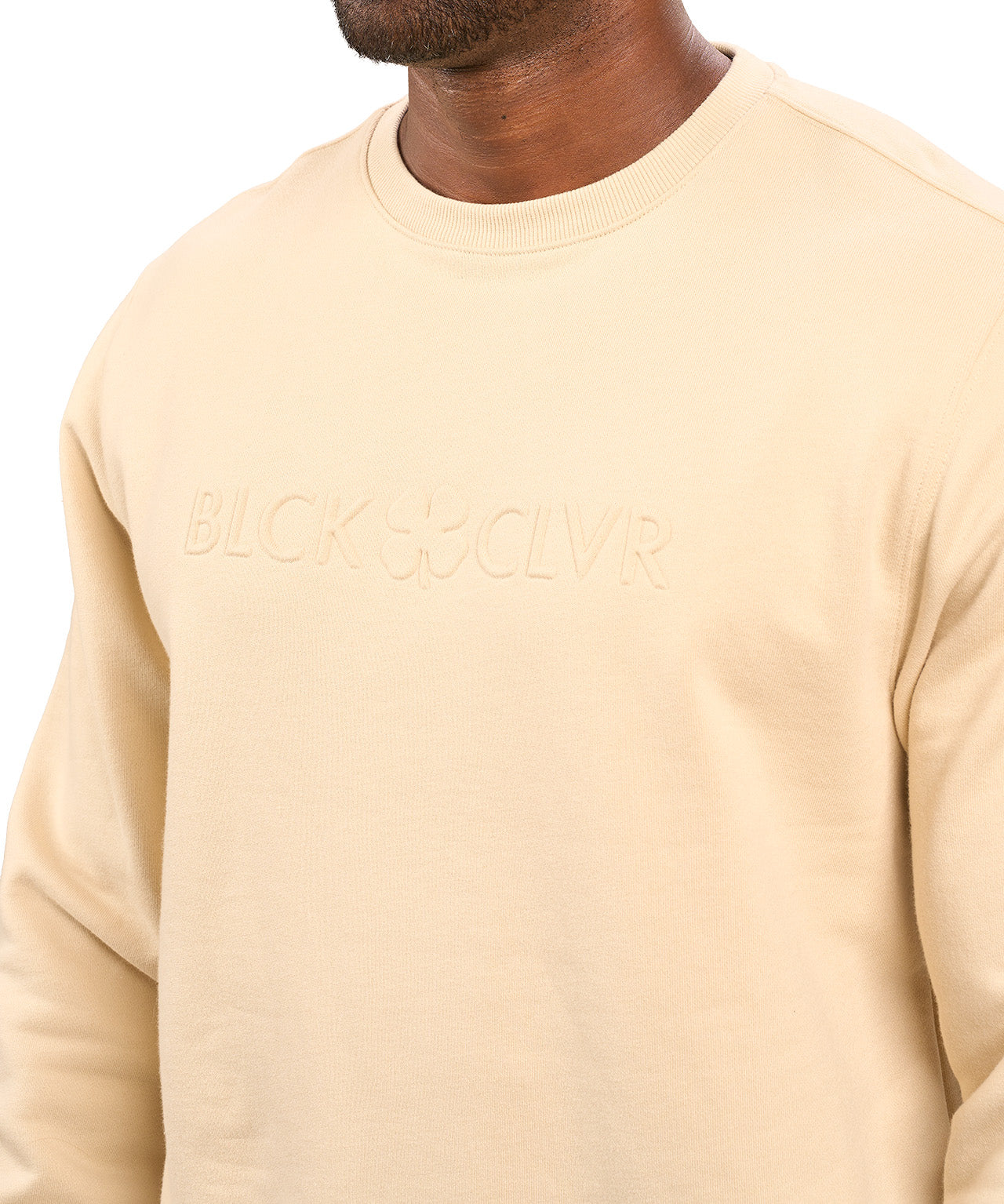 man wearing an oatmeal colored sweater from Black Clover with a 3d text BLCK CLVR on the chest