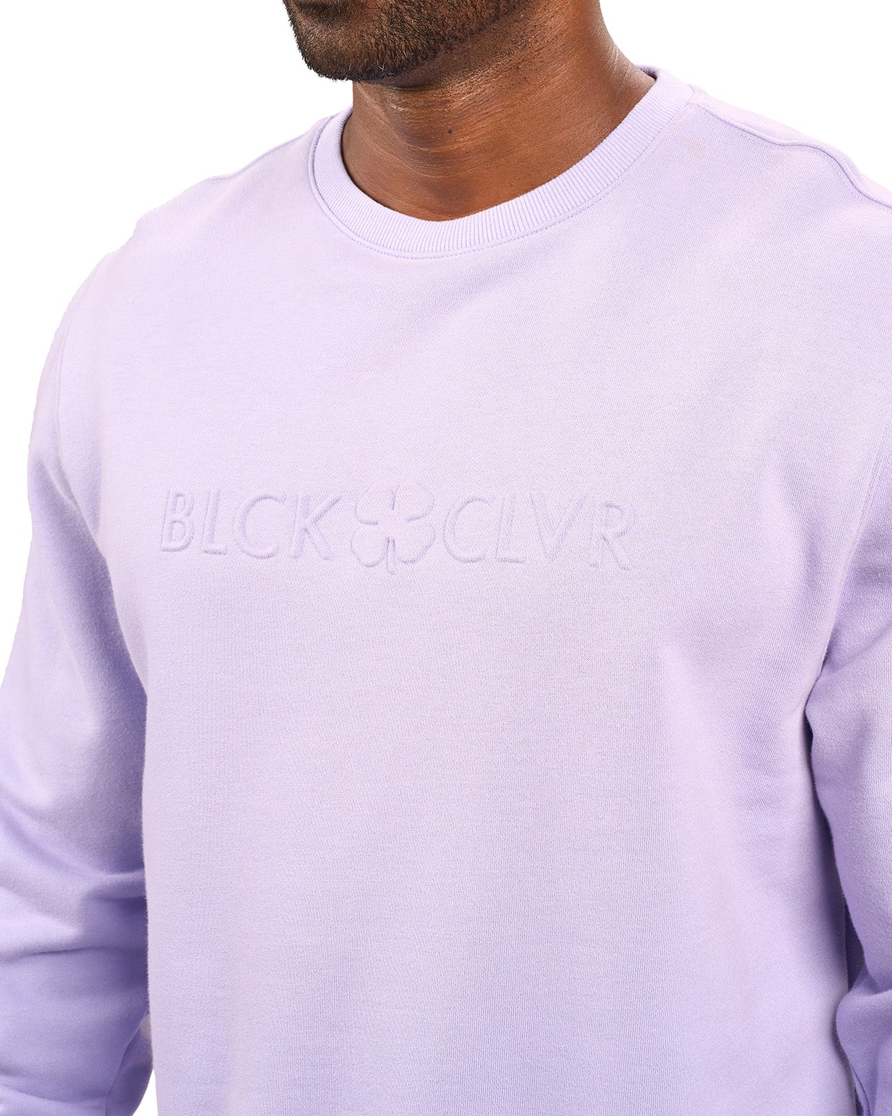 man wearing an light purple colored sweater from Black Clover with a 3d text BLCK CLVR on the chest