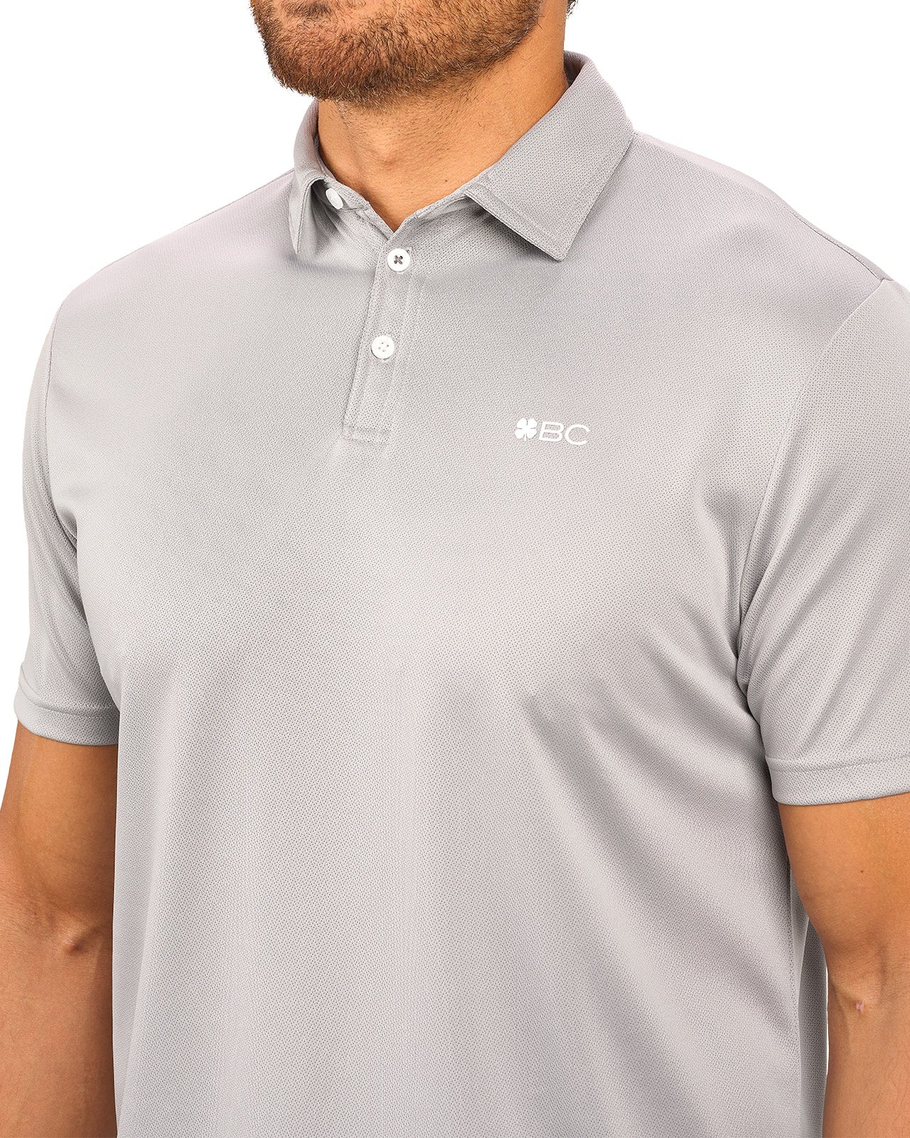 Man wearing a light grey polo from Black Clover with a small BC logo on the left chest