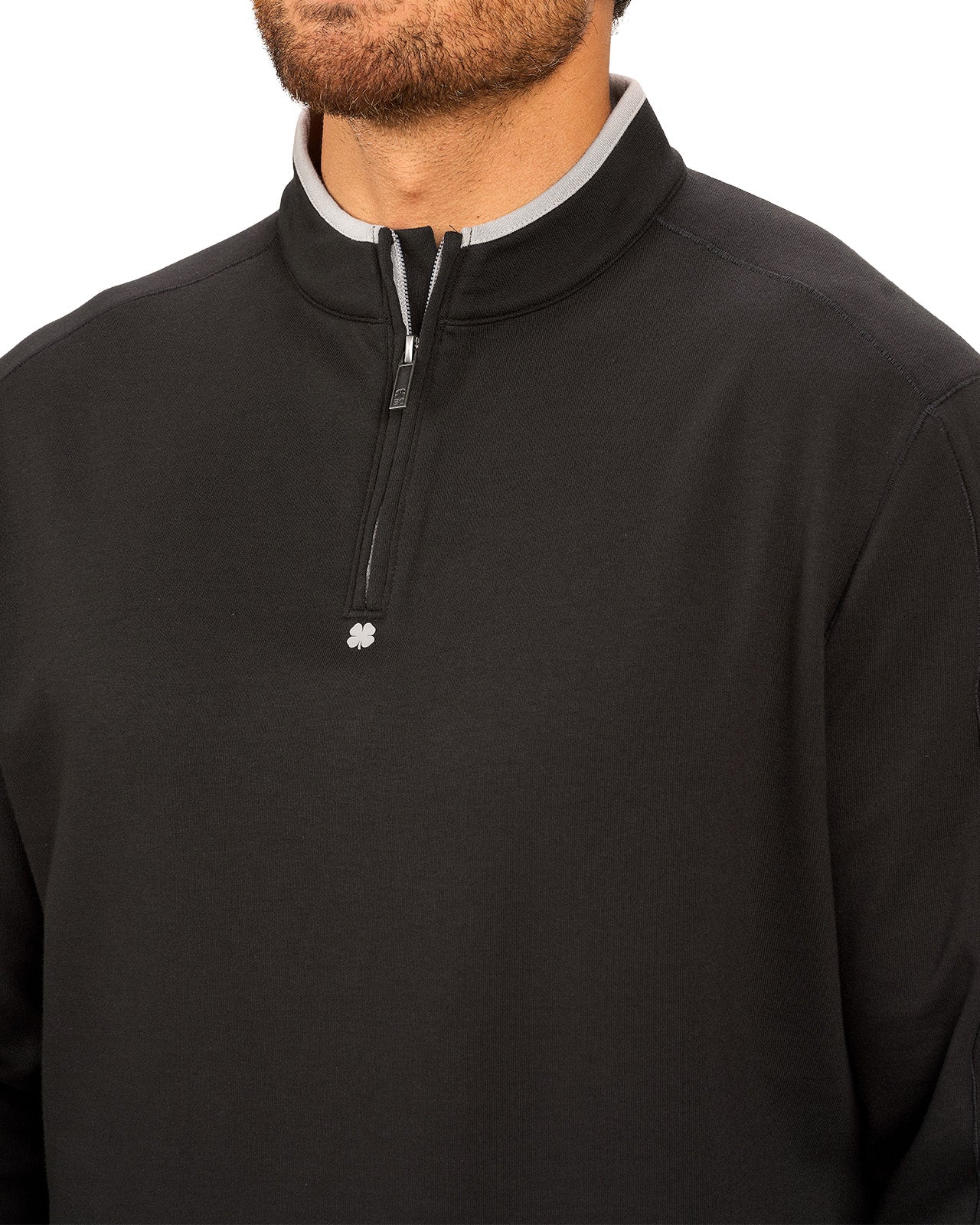 Man wearing a black quarter zip sweater from Black Clover featuring a small clover below the zipper