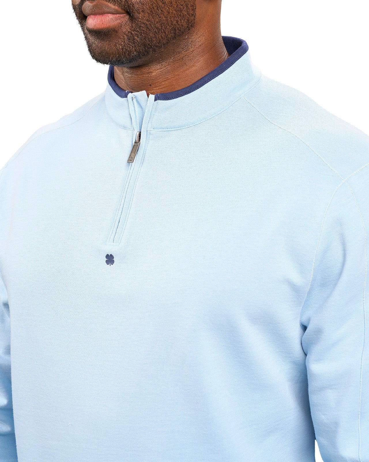 Man wearing a light blue quarter zip sweater from Black Clover featuring a small clover below the zipper