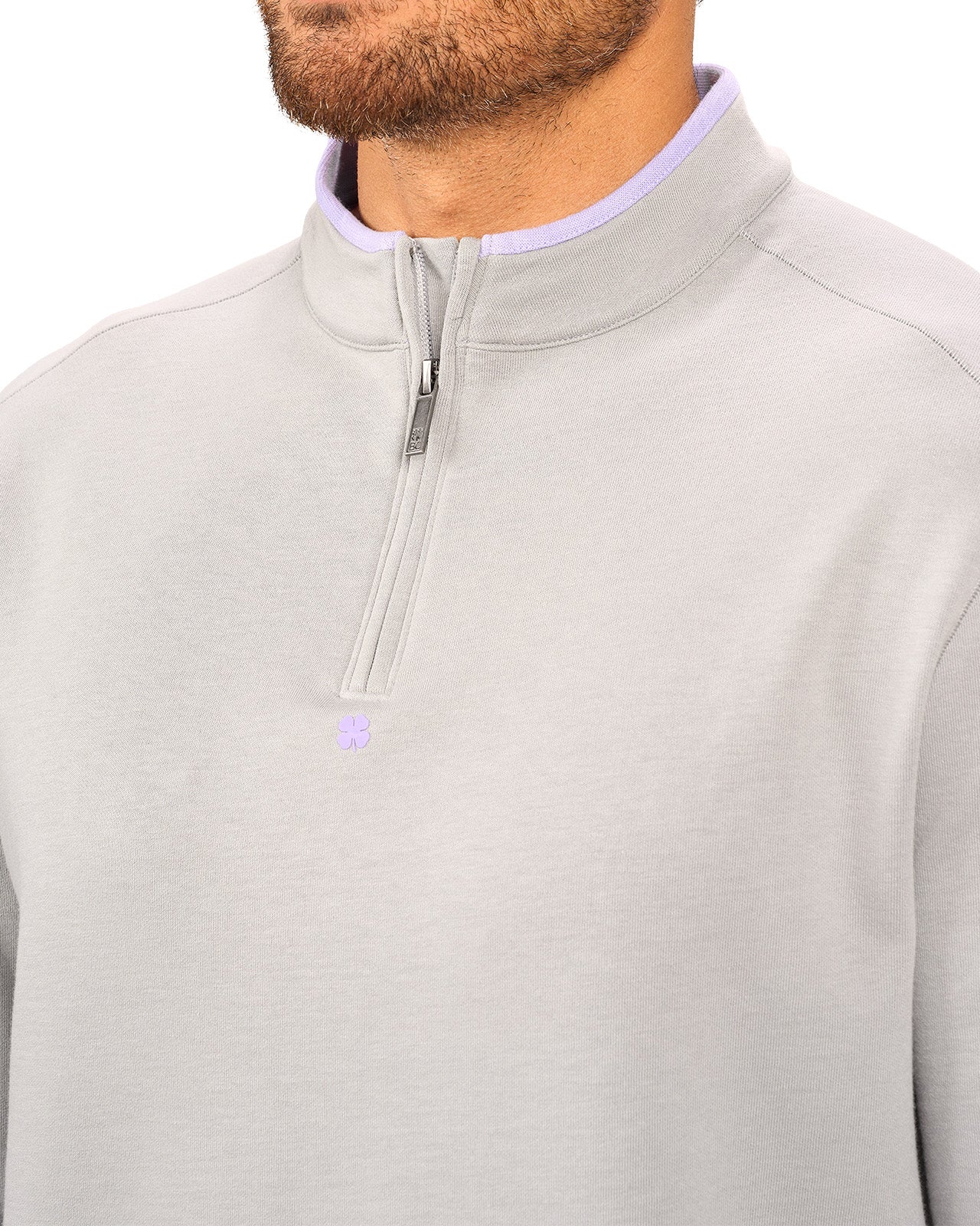 Man wearing a light grey quarter zip sweater from Black Clover featuring a small clover below the zipper