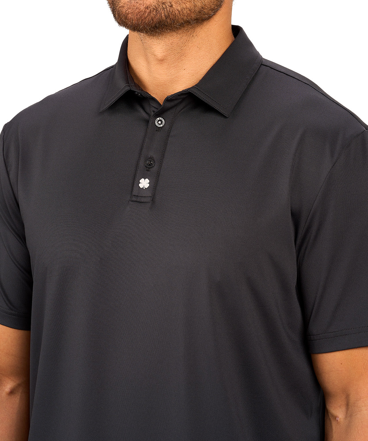 Man wearing black polo from black clover featuring a small clover logo below the bottom button