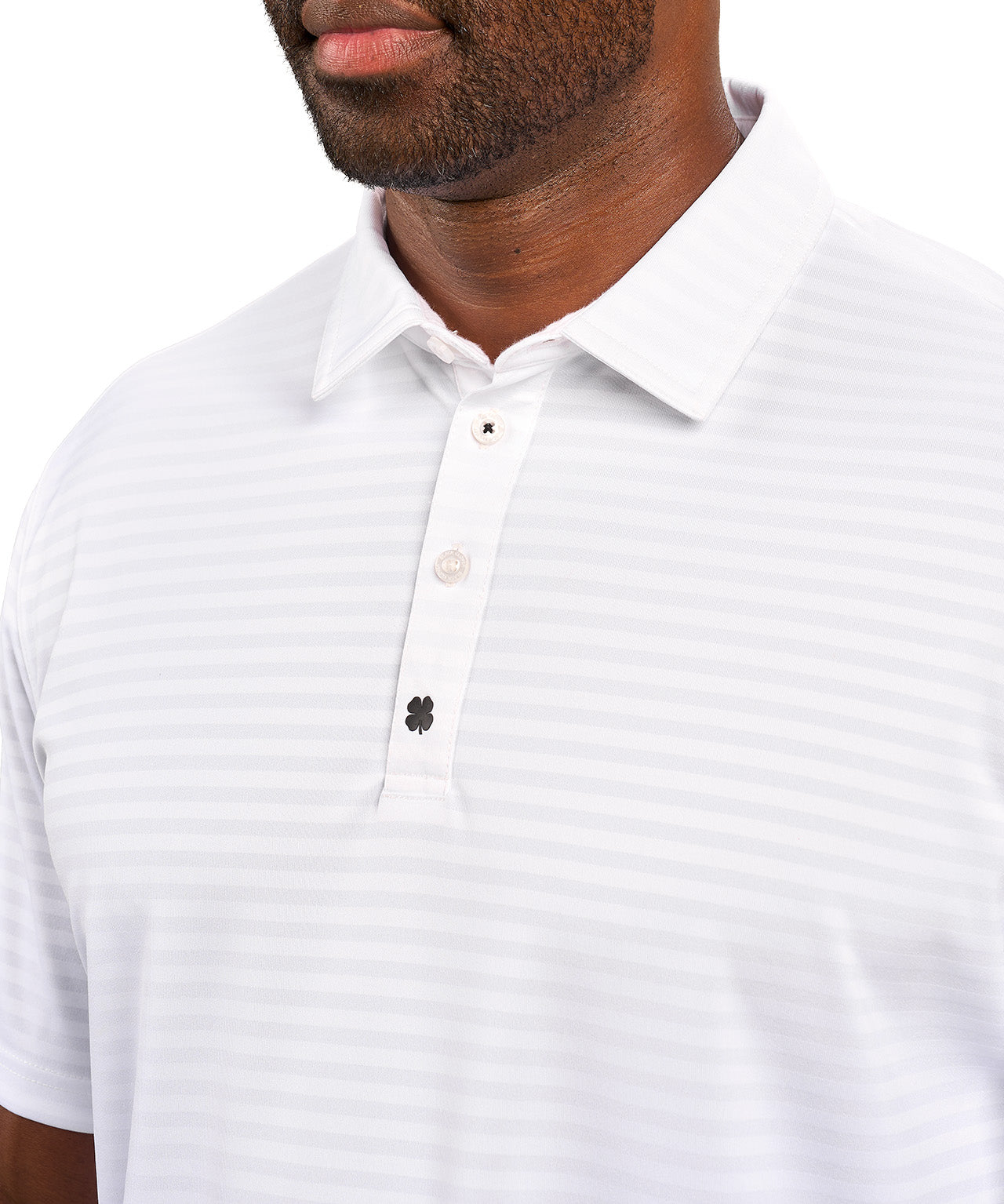 Man wearing striped white polo from Black Clover featuring small clover logo below the bottom button