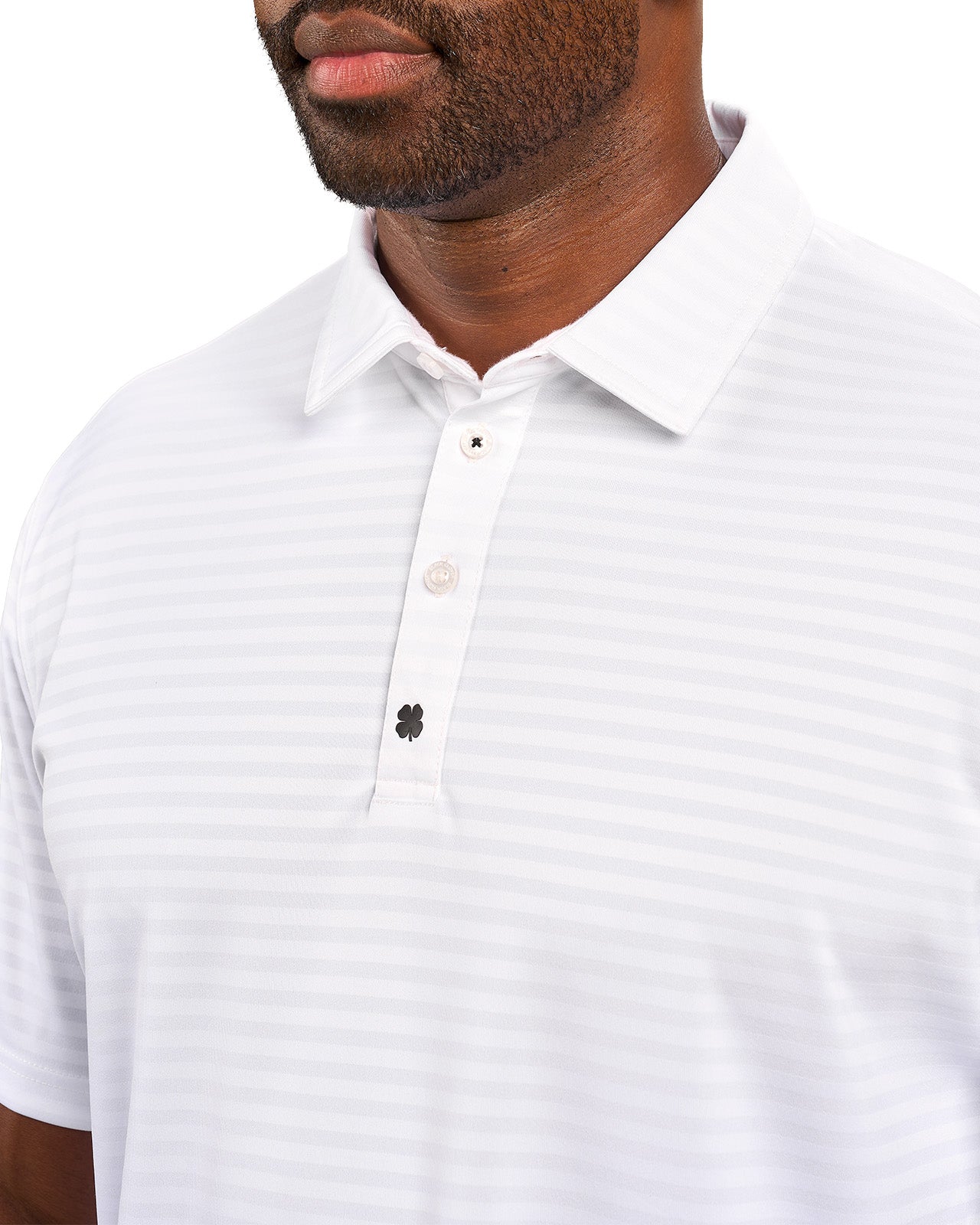 Man wearing striped white polo from Black Clover featuring small clover logo below the bottom button