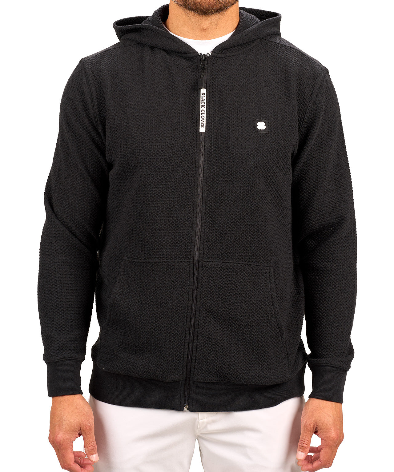 Man wearing black zip up hoodie from Black Clover featuring small clover icon on the left chest